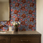 Bold floral wallpaper with red and coral blooms in a rustic bathroom setting.