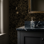 Gold floral and paisley wallpaper in elegant bathroom setting with black marble countertop.