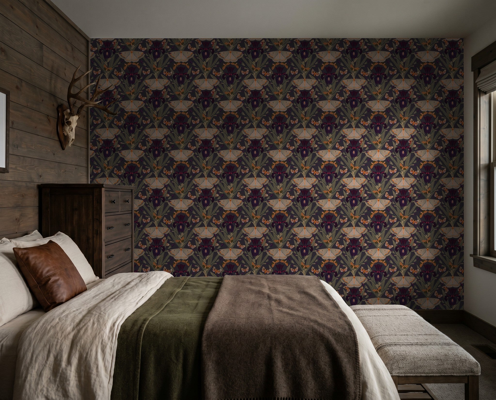 Moody floral wallpaper with moths and irises in a rustic bedroom setting.
