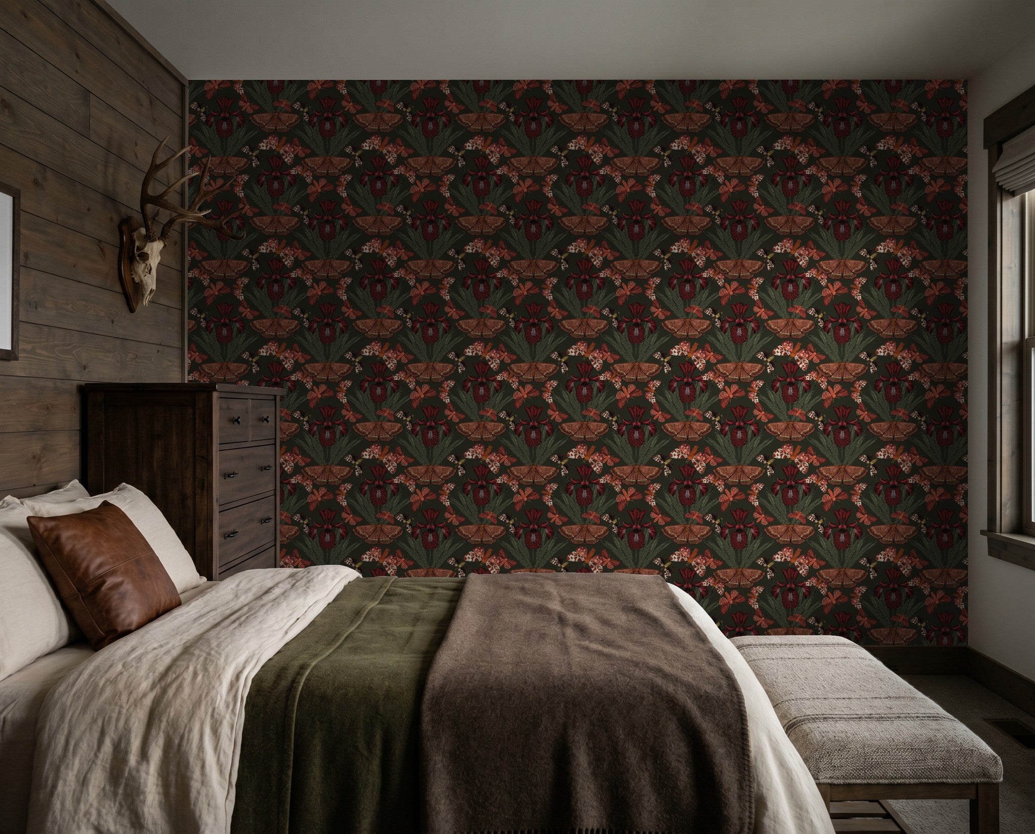 Moody floral wallpaper with ruby moths and olive foliage in a rustic bedroom.