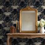 Navy wallpaper with moths and irises behind ornate mirror and wooden table.